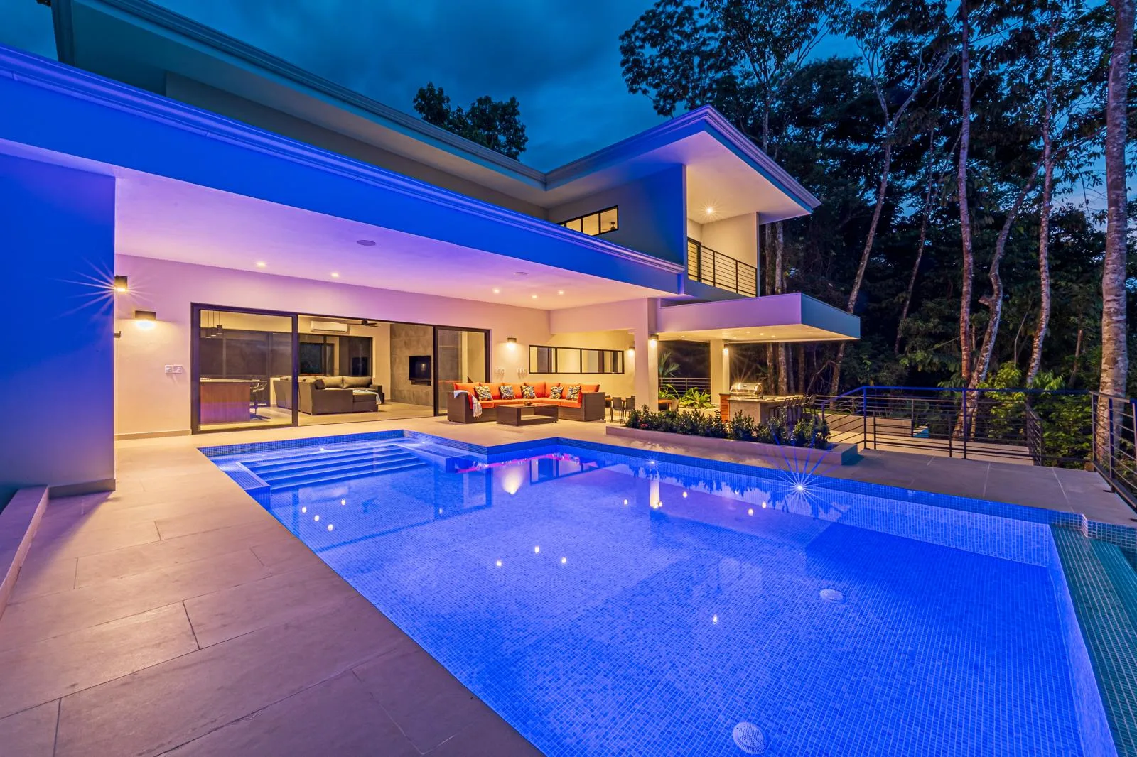 Pool terrace at dusk with layered exterior and interior lighting