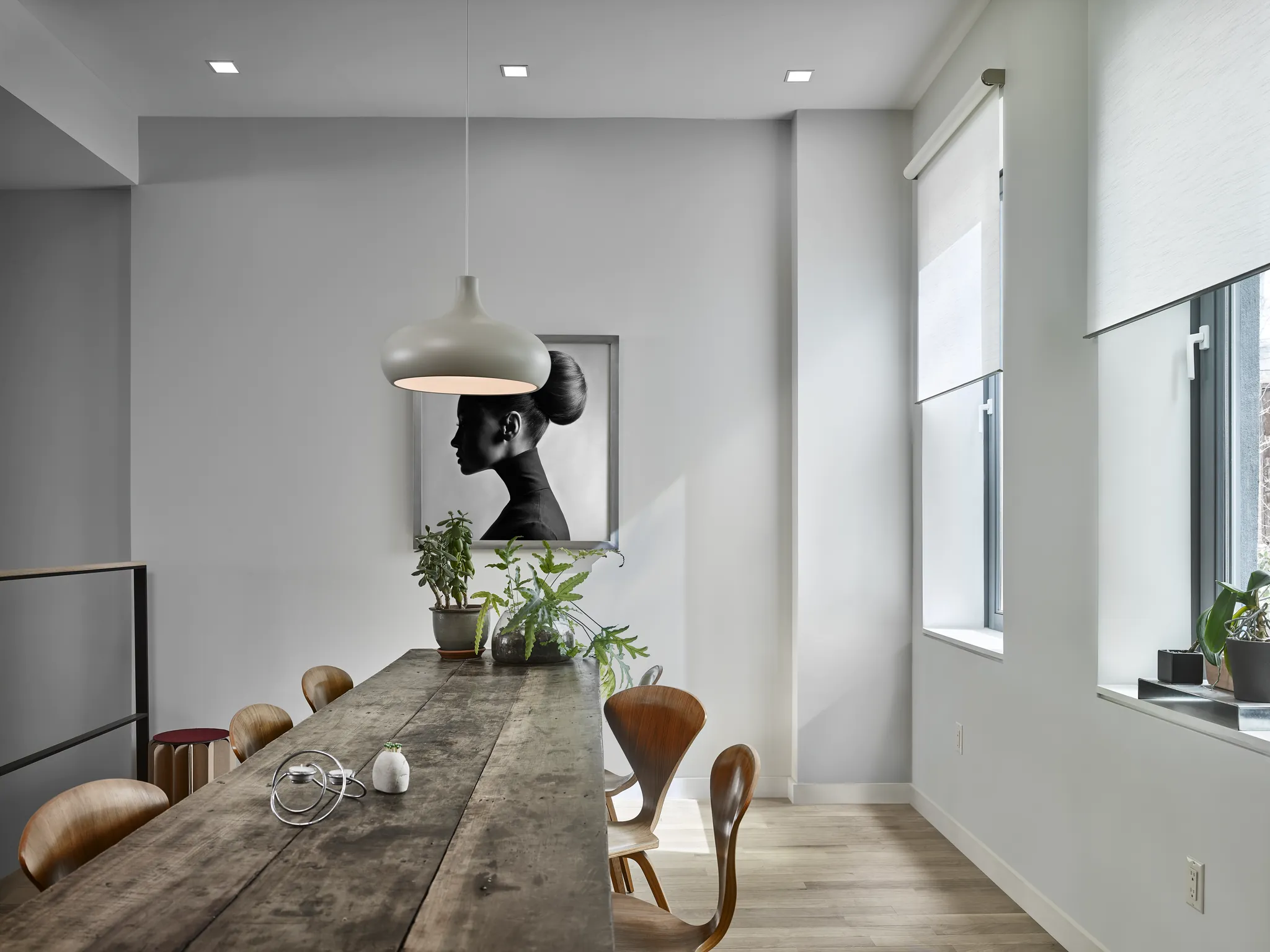 New York loft dining room with a pendant over a reclaimed-wood table, recessed lighting, and motorized roller shades